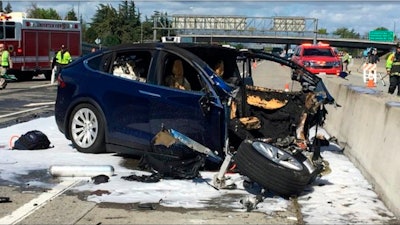 In this March 23, 2018 file photo provided by KTVU, emergency personnel work a the scene where a Tesla electric SUV crashed into a barrier on U.S. Highway 101 in Mountain View, Calif. Tesla says, Saturday, March 31, the vehicle in a fatal crash last week in California was operating on Autopilot, the latest accident to involve self-driving technology. The automaker says the driver, who was killed in the accident, did not have his hands on the steering wheel for six seconds before the crash. Tesla says its Autopilot feature, which can keep speed, change lanes and self-park, requires drivers to keep their eyes on the road and hands on the wheel to take control of the vehicle to avoid accidents.