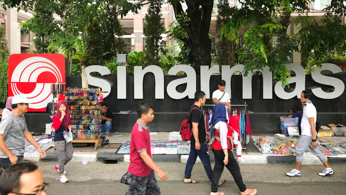In this Oct. 1, 2017 file photo, people walks past Sinarmas Land Plaza during a car-free day at the main business district in Jakarta, Indonesia. Greenpeace has ended a five-year truce with one of the world's largest pulp and paper companies, accusing it of cutting down tropical forests in Indonesia during the entire time the two were cooperating on conservation.
