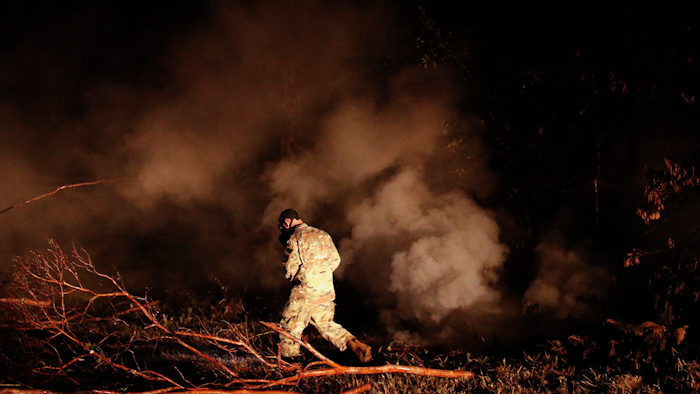 Sgt. 1st Class Carl Satterwaite, of the U.S. National Guard, tests air quality near cracks emitting volcanic gases from a lava flow in the Leilani Estates subdivision near Pahoa, Hawaii Thursday, May 10, 2018. Kilauea has destroyed more than 35 structures since it began releasing lava from vents about 25 miles (40 kilometers) east of the summit crater.