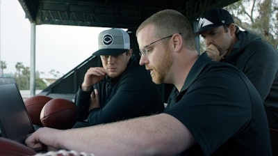 In this April 19, 2018, photo provided by Wilson Sporting Goods, quarterback Sam Darnold, left, and his mentor, former quarterback Jordan Palmer, right, look on as Wilson Labs engineer Dan Hare explains data gathered from throwing a football using the Wilson Connected Football System, at San Clemente High School in San Clemente, Calif. Darnold, the New York Jets rookie quarterback, was at his old stomping grounds in California last month tossing 'smart' footballs equipped with computer chips with Palmer, that were calculating his every throw.