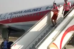 In this photo taken Monday, May 16, 2018, and released by a passenger who wishes to remain anonymous, ground crew are seen leaving the Sichuan Airline flight that made an emergency landing in Chengdu in southwestern China's Sichuan province. Chinese authorities and Airbus are investigating why the plane's cockpit windshield detached during a flight, forcing an emergency landing in an unusual mishap in one of the world's fastest growing aviation markets.