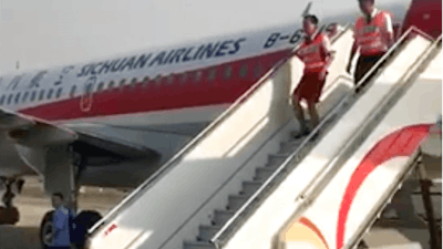 In this photo taken Monday, May 16, 2018, and released by a passenger who wishes to remain anonymous, ground crew are seen leaving the Sichuan Airline flight that made an emergency landing in Chengdu in southwestern China's Sichuan province. Chinese authorities and Airbus are investigating why the plane's cockpit windshield detached during a flight, forcing an emergency landing in an unusual mishap in one of the world's fastest growing aviation markets.