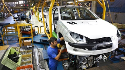 In this Oct. 11, 2014 file photo, an Iranian worker assembles a Peugeot 206 at the state-run Iran-Khodro automobile manufacturing plant near Tehran, Iran. From brand-new airplanes to oilfields, billions of dollars of deals stand on the line for international corporations as President Donald Trump weighs whether to pull America out of Iran's nuclear deal with world powers.