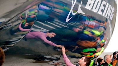 In this Feb. 5, 2018, file photo, Boeing worker Paul Covaci reaches out to touch a Boeing 737 MAX 7, the newest version of Boeing's fastest-selling airplane, during a debut for employees and media of the new jet in Renton, Wash. The U.S. withdrawal from the Iran nuclear deal means Boeing's licenses to sell billions of dollars in commercial jetliners to Iran will be revoked, Treasury Secretary Steven Mnuchin said Tuesday, May 8.