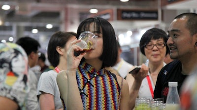 In this Thursday, May 17, 2018, photo, a woman drinks beer at the 2018 Craft Beer of China Exhibition in Shanghai. Hundreds of craft beer enthusiasts, investors and brewers are attending an exhibition in Shanghai dedicated to expanding the palette of Chinese consumers and promoting sales of high-end brews.