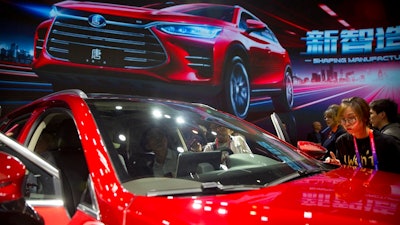 In this April 25, 2018, file photo, attendees look at the Tang SUV by Chinese automaker BYD after a press conference at the China Auto Show in Beijing. An industry group says Chinese passenger car sales expanded at a faster pace in April 2018 as growth in the world's biggest auto market picked up steam.