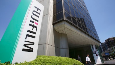 A man walks in front of Nishiazabu headquarters of Fujifilm Holdings Corporation in Tokyo, Monday, May 14, 2018. Copier company Xerox Corp. said Sunday it was ending an agreement to combine with Japan's Fujifilm Holdings and is entering a settlement deal with investors Carl Icahn and Darwin Deason.