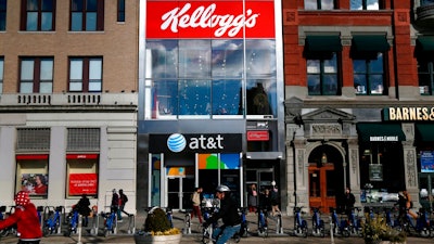 In this Dec. 14, 2017, file photo, people bike and walk by Kellogg's NYC Cafe at Union Square in New York. Kellogg Co. reports earnings Thursday, May 3, 2018.