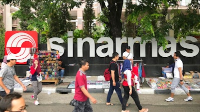In this Oct. 1, 2017 file photo, people walks past Sinarmas Land Plaza during a car-free day at the main business district in Jakarta, Indonesia. Greenpeace has ended a five-year truce with one of the world's largest pulp and paper companies, accusing it of cutting down tropical forests in Indonesia during the entire time the two were cooperating on conservation.