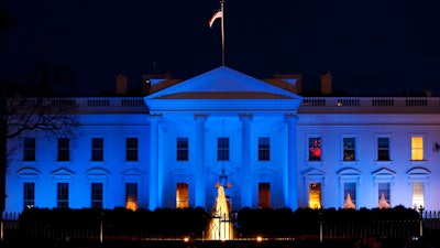 In this April 2, 2017, file photo, the White House is lit with blue lights in honor of World Autism Awareness Day in Washington. Top U.S. tech executives and researchers are gathering at a White House summit, Thursday, May 10, 2018, to press Trump administration officials on investing in artificial intelligence and crafting policies they hope will strengthen the economy without displacing jobs.