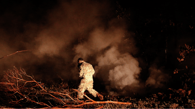 Sgt. 1st Class Carl Satterwaite, of the U.S. National Guard, tests air quality near cracks emitting volcanic gases from a lava flow in the Leilani Estates subdivision near Pahoa, Hawaii Thursday, May 10, 2018. Kilauea has destroyed more than 35 structures since it began releasing lava from vents about 25 miles (40 kilometers) east of the summit crater.