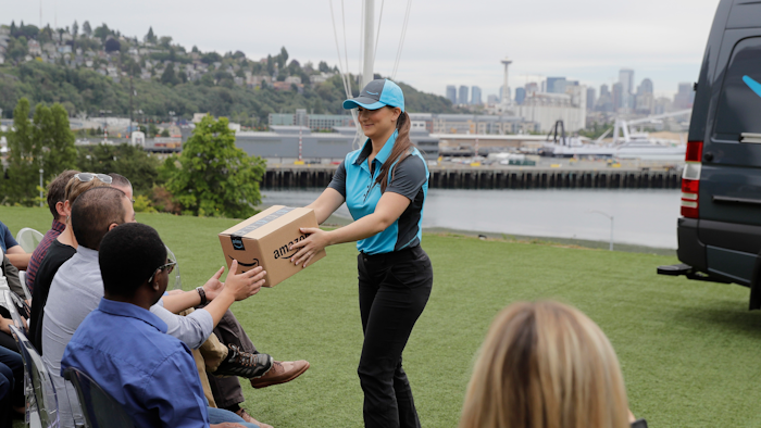 Parisa Sadrzadeh, center, a senior manager of logistics for Amazon.com, demonstrates a package delivery for journalists, Wednesday, June 27, 2018, in Seattle, at a media event for Amazon to announce a new program that lets entrepreneurs around the country launch businesses that deliver Amazon packages. It's another way for Amazon to gain greater control over how its packages are delivered.