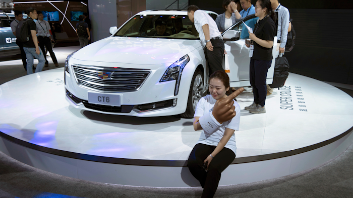 A woman poses for a photo in front of a CT6 Cadillac during the Consumer Electronics Show Asia 2018 in Shanghai, China on Friday, June 15, 2018. President Donald Trump is poised to hike the price of Chinese-made flat-screen TVs and ultrasound machines for American buyers. They are part of a tech imports worth up to $50 billion on which Trump is preparing to slap 25 percent tariffs in response to complaints Beijing steals or pressures foreign companies to hand over technology.