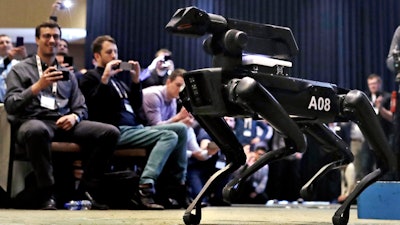 In this Thursday, May 24, 2018, photo, a Boston Dynamics SpotMini robot is walks through a conference room during a robotics summit in Boston. It's never been clear whether robotics company Boston Dynamics is making killing machines, household helpers, or something else entirely. But the secretive firm, which for nine years has unnerved viewers with YouTube videos of robots that jump, gallop or prowl like animal predators, is starting to emerge from a quarter-century of stealth.