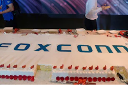 Workers walk past a giant cake to celebrate Taiwan-based contract manufacturing giant Foxconn's 30th anniversary of its first investment in Shenzhen, south China's Guangdong province Wednesday, June 6, 2018. The head of Taiwan's Foxconn, which assembles Apple iPhones and other tech products, says Washington's dispute with China is over technology rather than trade.