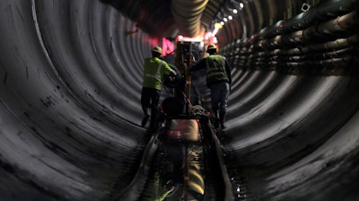 In this Wednesday, May 16, 2018 photo, tunnel workers push equipment up a rail track to a machine boring a 2.5-mile bypass tunnel for the Delaware Aqueduct, in Marlboro, N.Y. Hard-hat workers are toiling deep underground, 55 stories beneath the Hudson River, to eliminate gushing leaks in an aging tunnel that carries half the city's water supply over 85 miles from Catskill Mountain reservoirs.
