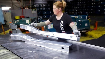 In this April 30, 2015, file photo, United Auto Workers line worker Crystal McIntyre unloads parts from a stamping machine at the General Motors Pontiac Metal Center in Pontiac, Mich. If President Donald Trump delivers on threats to slap 25 percent tariffs on imported automobiles and parts, experts say it will cut auto sales and cost jobs in the U.S., Canada and Mexico.