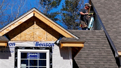 In this April 23, 2018, file photo, a worker installs vinyl siding on a new home in Auburn, N.H. On Monday, June 18, the National Association of Home Builders/Wells Fargo releases its June index of builder sentiment.