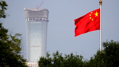 In this Thursday, June 14, 2018, file photo, a Chinese national flag at Tiananmen Square flutters against the capital city tallest skyscraper China Zun Tower under construction at the Central Business District in Beijing. China has threatened 'comprehensive measures' in response to U.S. President Donald Trump's new tariff hike, raising the possibility Beijing might target operations of American companies.