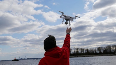 In this April 29, 2018, file photo, a drone operator helps to retrieve a drone after photographing over Hart Island in New York. Science advisers to the federal government say safety regulators should do more to speed the integration of commercial drones into the nation's airspace. The National Academies of Science, Engineering and Medicine said in a report Monday that federal safety regulators are often 'overly conservative' and need to balance the overall benefits of drones instead of focusing only on their risk to airplanes and helicopters.
