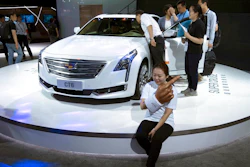 A woman poses for a photo in front of a CT6 Cadillac during the Consumer Electronics Show Asia 2018 in Shanghai, China on Friday, June 15, 2018. President Donald Trump is hiking the price of Chinese-made forklift trucks and X-ray machines for American buyers. They are part of a $50 billion list of Chinese exports targeted for a 25 percent tariff hike in response to complaints Beijing steals or pressures foreign companies to hand over technology.