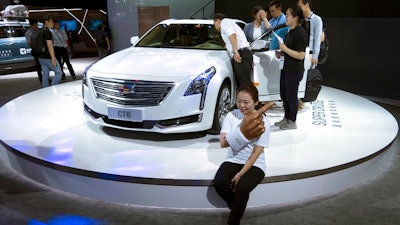 A woman poses for a photo in front of a CT6 Cadillac during the Consumer Electronics Show Asia 2018 in Shanghai, China on Friday, June 15, 2018. President Donald Trump is hiking the price of Chinese-made forklift trucks and X-ray machines for American buyers. They are part of a $50 billion list of Chinese exports targeted for a 25 percent tariff hike in response to complaints Beijing steals or pressures foreign companies to hand over technology.