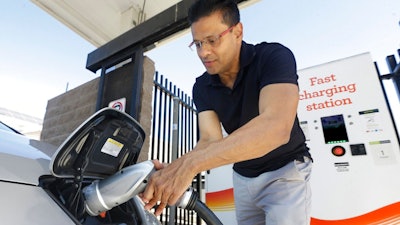 In this Sept. 17, 2015, file photo, Darshan Brahmbhatt, plugs a charger into his electric vehicle at the Sacramento Municipal Utility District charging station in Sacramento, Calif. California utilities will invest nearly $768 million to expand a network of charging stations and other infrastructure for electric vehicles as the state moves toward a goal of 5 million zero-emission cars on the roads by 2030. The California Public Utilities Commission voted 5-0 Thursday, May 31, 2018, to fund programs statewide, with an emphasis on building facilities in disadvantaged communities.