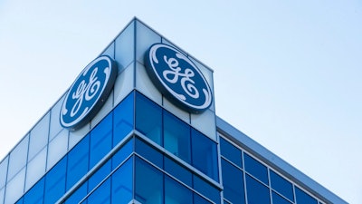 In this Jan. 16, 2018, file photo, the General Electric logo is displayed at the top of their Global Operations Center in the Banks development of downtown Cincinnati. A year after taking over an ailing American conglomerate, CEO John Flannery is calving off larger chunks of General Electric, spinning off its health care business and selling its stake in the oil services company, Baker Hughes.