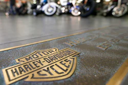 In this April 26, 2017, file photo, rows of motorcycles are behind a bronze plate with corporate information on the showroom floor at a Harley-Davidson dealership in Glenshaw, Pa. Harley-Davidson, facing rising costs from new tariffs, will begin shifting the production of motorcycles heading for Europe from the U.S. to factories overseas.