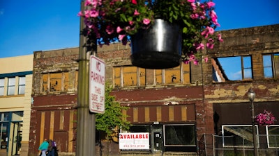 In this June 16, 2017, file photo, dilapidated storefronts stand along baskets of pink petunias that hang from light posts all over town, watered regularly by residents trying to make their city feel alive again in Aberdeen, Wash. From drivers paying more for gas and families bearing heavier child care costs to workers still awaiting decent pay raises to couples struggling to afford a home, people throughout the economy are straining to succeed despite the economy’s gains.