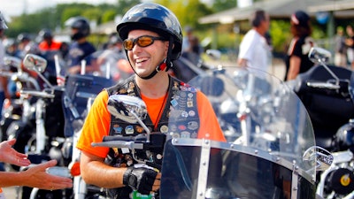 In this Aug. 31, 2013 file photo, Gov. Scott Walker laughs before riding in the Harley-Davidson 110th Anniversary Parade in Milwaukee, Wis. The ceremonial groundbreaking for a massive $10 billion Foxconn factory complex in Wisconsin was supposed to be evidence that the manufacturing revival fueled by President Donald Trump's 'America First' policy is well underway. But an announcement this week by Harley-Davidson that it is moving some production of motorcycles overseas to avoid tariffs is fueling unease among voters in Wisconsin _ a state Trump barely won and where fellow Republican Gov. Scott Walker is on the ballot.