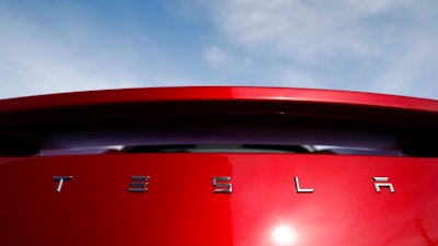 In this April 15, 2018, file photo the sun shines off the rear deck of a roadster on a Tesla dealer's lot in the south Denver suburb of Littleton, Colo. Electric car maker Tesla Inc. is laying off about 3,600 white-collar workers as it slashes costs in an effort to become profitable. CEO Elon Musk says in an e-mail to workers Tuesday, June 12, that the cuts amount to about 9 percent of the company’s workforce of 40,000.