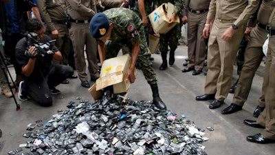 A Thai law-enforcement officer unloads a box full of mobile batteries during a raid at a factory accused of importing and processing electronic waste in the suburbs of Bangkok, Thailand on Thursday, June 21, 2018. Thai authorities, who last month began a series of raids on factories accused of illegally importing and processing electronic waste, have said they may use special executive powers allowed the military government to issue a total ban on the import of such potentially toxic materials.