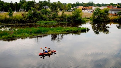 In this Aug. 14, 2017 file photo, a couple kayak on the Rogue River adjacent to where Wolverine World Wide's tannery once stood, in Rockford, Mich. The Michigan Department of Environmental Quality is investigating the connection between old waste drums in the area and an old Wolverine World Wide tannery waste dump nearby. Some private wells in the area have tested positive for elevated levels of per- and polyfluoroalkyl substances called PFAS, also called perfluorinated chemicals, or PFCs. A government report shows that a family of industrial chemicals turning up in public water supplies around the country threatens human health at concentrations seven to 10 times lower than previously realized. The chemicals are called perfluoroalkyl and polyfluoroalkyl.