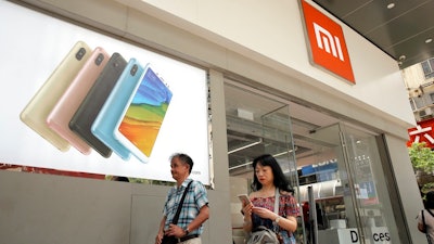 In this Wednesday, June 20, 2018, photo, people walk past a Xiaomi store in Hong Kong. Xiaomi, a Chinese startup that helped to pioneer the trend toward ultra-low-priced smartphones, is preparing for what would be the biggest initial public offering since e-commerce giant Alibaba's in 2014. The 8-year-old is a star among the Chinese unicorns, a term that refers to startup companies that are valued at more than $1 billion. It has a dedicated Chinese fan base and its media-savvy leader is an Asian celebrity. But it is untested outside the region.