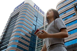 In this May 8, 2018, file photo, a woman passes by a ZTE building in Beijing, China. Chinese tech giant ZTE Corp.'s chairman promised no further compliance violations and apologized to customers in a letter Friday, June 8, 2018, for disruptions caused by its violation of U.S. export controls, a newspaper reported.