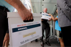 Faith leader the Rev. Paul Benz, center, and Shankar Narayan, legislative director of the ACLU of Washington, right, stand with others as they wait to deliver petitions at Amazon headquarters, Monday, June 18, 2018, in Seattle. Representatives of community-based organizations urged Amazon at a news conference to stop selling its face surveillance system, Rekognition, to the government. They later delivered the petitions to Amazon.