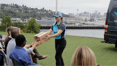 Parisa Sadrzadeh, center, a senior manager of logistics for Amazon.com, demonstrates a package delivery for journalists, Wednesday, June 27, 2018, in Seattle, at a media event for Amazon to announce a new program that lets entrepreneurs around the country launch businesses that deliver Amazon packages. It's another way for Amazon to gain greater control over how its packages are delivered.