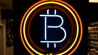 In this Feb. 7, 2018 file photo, a neon sign hanging in the window of Healthy Harvest Indoor Gardening in Hillsboro, Ore., shows that the business accepts bitcoin as payment. A raft of recent cyber-security firms and governments now cite the rising trend of ‘crypto-jacking’ _ in which devices are infected with invisible malicious cryptocurrency mining software that uses the computing power of victims’ devices to mine virtual currency _ as the main cyber security threat to businesses and consumers worldwide.