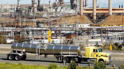 This March 9, 2010, file photo shows a tanker truck passing the Chevron oil refinery in Richmond, Calif. A U.S. judge who held a hearing about climate change that received widespread attention has thrown out the underlying lawsuits that sought to hold big oil companies liable for the role of fossil fuels in the Earth's warming environment. Judge William Alsup in San Francisco said Monday, June 25, 2018, that Congress and the president, not a federal judge, were best suited to address fossil fuels' contribution to global warming.