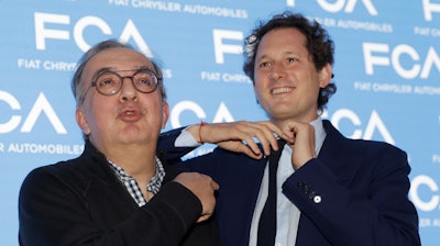 John Elkann president of the FCA Italy group, right, removes his necktie to give it to Fiat Chrysler CEO Sergio Marchionne prior to a press conference at the FCA headquarters, in Balocco, Italy, Friday, June 1, 2018. In his last big presentation as CEO of Fiat Chrysler before retiring, Sergio Marchionne announced a big investment push to make more electrified cars, while acknowledging that traditional engines will continue to dominate production for some time.
