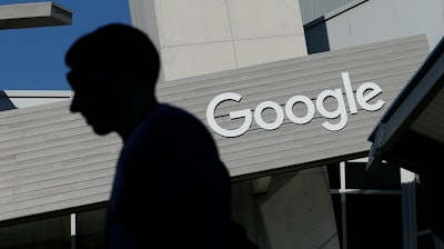 In this Nov. 12, 2015, file photo, a man walks past a building on the Google campus in Mountain View, Calif. Voters in a Northern California city will decide whether Google and other tech companies should help pay for the traffic headaches and other problems that have arisen as their workforces have swelled during the past decade. The city council in Mountain View, California, voted Tuesday, June 26, 2018, to place a measure on the November ballot asking residents to authorize taxing businesses between $9 and $149 per employee.