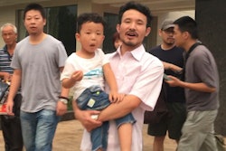 In this June 28, 2017 file image taken from video, Chinese labor activists Hua Haifeng, center, carries his son Bo Bo, and Li Zhao, second left, leave a police station after being released in Ganzhou in southern China's Jiangxi Province. China Labor Watch says three activists who were arrested while investigating abuses at Ivanka Trump's Chinese suppliers last year were released from bail on Tuesday June 26, 2018, but questions remain about their ability to live and work freely.