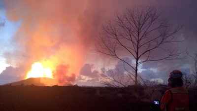 In this photo provided by the U.S. Geological Survey, crews make visual observations of lava activity at fissure 8, Thursday, May 31, 2018 near Pahoa, Hawaii. Fountain heights Thursday morning continued to reach 230 to 260 feet (70 to 80 meters) above ground level. The fountaining feeds a lava flow that is moving to the northeast along Highway 132 into the area of Noni Farms road.