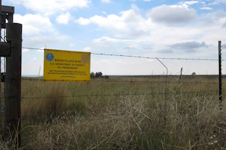 This Aug. 11, 2017 photo shows a 'no trespassing' sign hanging on a fence surrounding part of the former Rocky Flats nuclear weapons plant near Denver. Rocky Flats was once the site of a plant that made plutonium triggers for nuclear weapons. Part of the site was designated a refuge after a $7 billion cleanup, but the area where plutonium was handled remains off-limits. On Sunday, June 3, 2018, the refuge manager harshly criticized a local Colorado health officer who questioned the safety of the site and expressed doubt about whether the U.S. government's assurances about the site could be trusted.