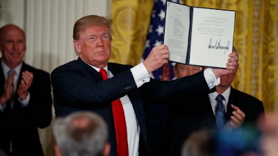 President Donald Trump shows off a 'Space Policy Directive' after signing it during a meeting of the National Space Council in the East Room of the White House, Monday, June 18, 2018, in Washington.