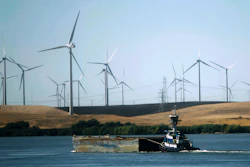 In this Sept. 23, 2013, file photo, a tugboat pushes a barge down the Sacramento River past wind turbines near Rio Vista, Calif. A contentious proposal to link oversight of California's electric grid with other western states faces a crucial test Tuesday, June 19, 2018, in a state Senate committee.