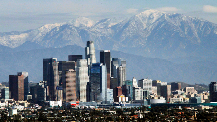 In this Dec. 31, 2014, file photo, the snow-capped San Gabriel Mountains provide a backdrop to the downtown Los Angeles skyline as seen from Kenneth Hahn State Recreation Area in Baldwin Hills. California greenhouse gas emissions fell below 1990 levels, meeting an early target years ahead of schedule and putting the state well on its way toward reaching long-term goals to fight climate change, officials said Wednesday, July 11, 2018.