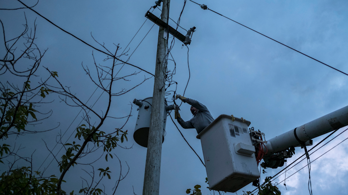 In this July 12, 2018 photo, a laborer from the Puerto Rico Power Authority works to restore power in Adjuntas, Puerto Rico. Puerto Rico's electrical grid is still shaky after Hurricane Irma brushed past the island as a Category 5 storm last Sept. 6 and then Hurricane Maria made a direct hit as a Category 4 storm two weeks later, damaging up to 75 percent of transmission lines.