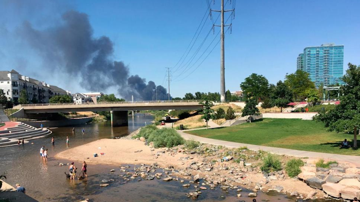 Firefighters are battling a large blaze at a metal recycling facility that sent up a large, black plume of smoke that could be seen for miles just north of downtown Denver, Tuesday, July 10, 2018. Fire crews from Denver and Adams County responded to the fire, which was reported at EVRAZ Recycling on Tuesday afternoon.